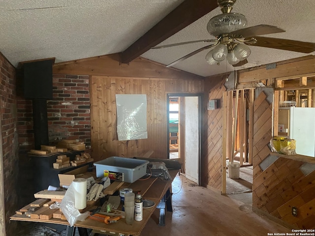 misc room with lofted ceiling with beams, wood walls, a textured ceiling, and ceiling fan