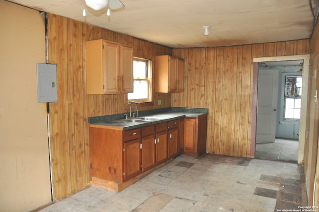 kitchen with electric panel, wooden walls, sink, and a healthy amount of sunlight