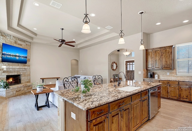 kitchen featuring hanging light fixtures, sink, a kitchen island with sink, and light hardwood / wood-style flooring