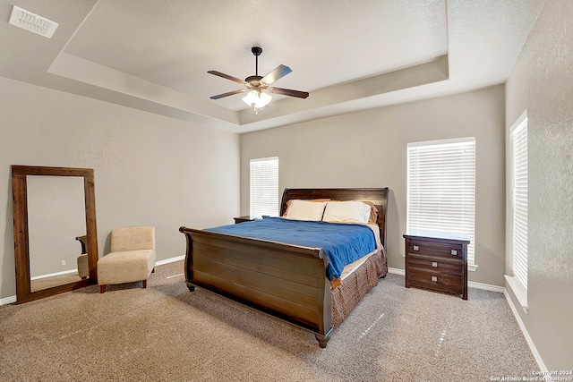 carpeted bedroom featuring ceiling fan, a textured ceiling, and a raised ceiling