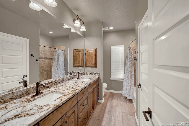 bathroom featuring toilet, hardwood / wood-style floors, a textured ceiling, vanity, and a shower with shower curtain