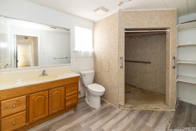 bathroom featuring hardwood / wood-style floors, vanity, a shower, toilet, and tile walls