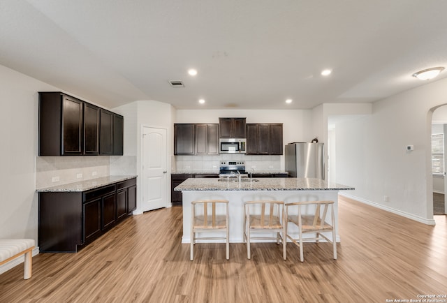 kitchen with stainless steel appliances, a kitchen island with sink, and light hardwood / wood-style flooring