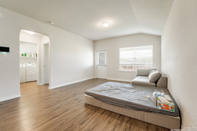 sitting room featuring washing machine and clothes dryer, hardwood / wood-style flooring, and vaulted ceiling