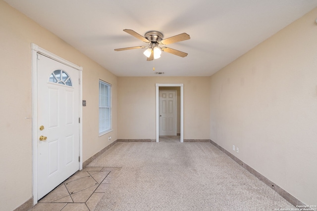 foyer entrance with ceiling fan and light carpet