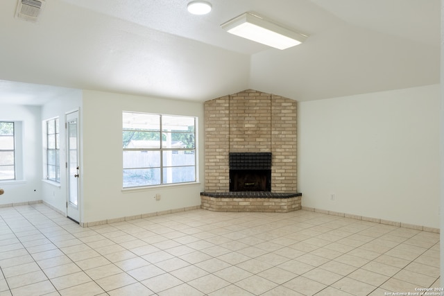 unfurnished living room featuring a brick fireplace, a wealth of natural light, lofted ceiling, and light tile patterned floors