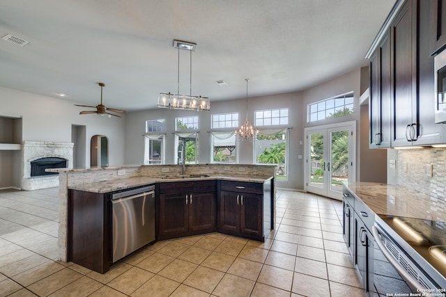 kitchen with sink, light stone counters, a fireplace, dark brown cabinets, and dishwasher