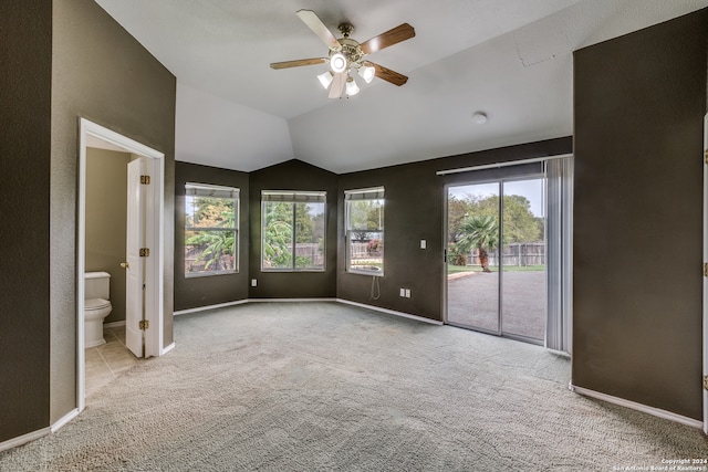 interior space featuring ensuite bathroom, ceiling fan, light carpet, and vaulted ceiling