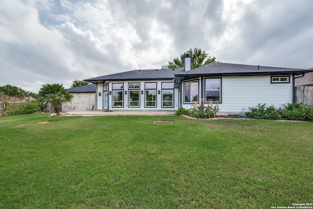 rear view of property featuring a lawn