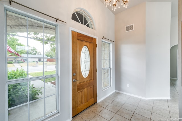 foyer entrance with a high ceiling, light tile patterned floors, and a notable chandelier