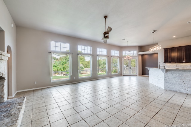 unfurnished living room featuring ceiling fan with notable chandelier, plenty of natural light, and light tile patterned floors