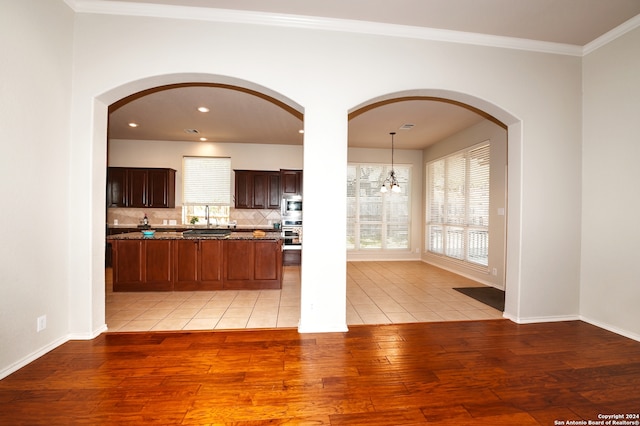 kitchen with light hardwood / wood-style floors, hanging light fixtures, a chandelier, crown molding, and stainless steel microwave