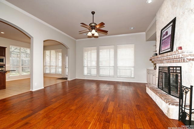 unfurnished living room with ceiling fan, wood-type flooring, ornamental molding, and a fireplace