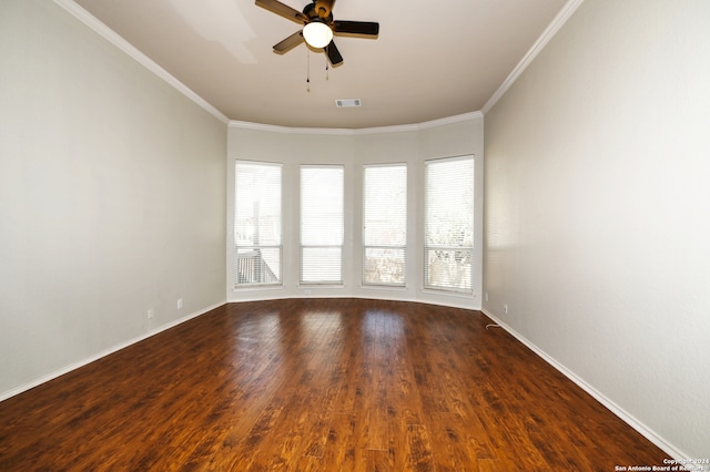 spare room featuring dark hardwood / wood-style flooring, ceiling fan, ornamental molding, and plenty of natural light