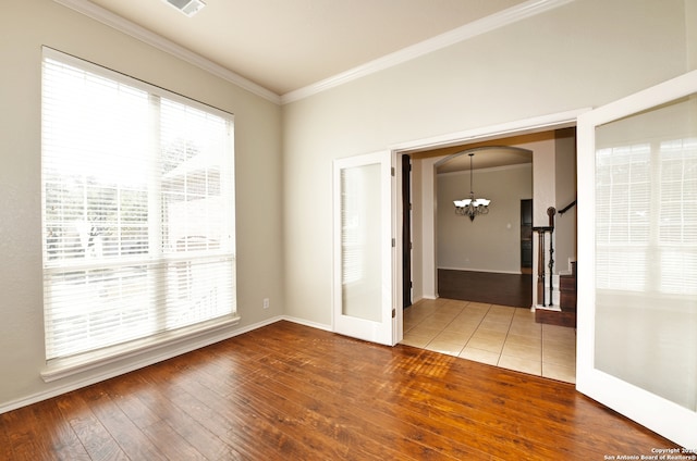 unfurnished room with hardwood / wood-style floors, an inviting chandelier, and ornamental molding