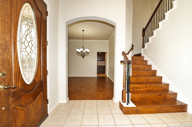 foyer featuring light wood-type flooring, a notable chandelier, and crown molding