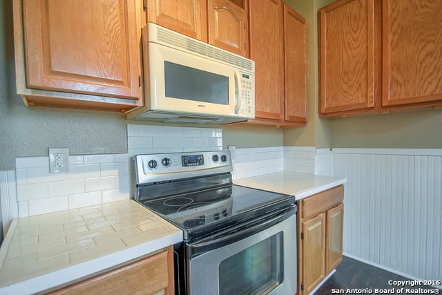 kitchen featuring backsplash, tile counters, and stainless steel range with electric stovetop