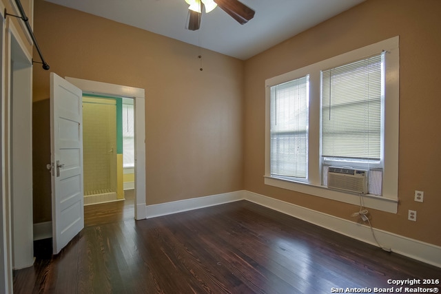 empty room with ceiling fan, cooling unit, and dark hardwood / wood-style flooring