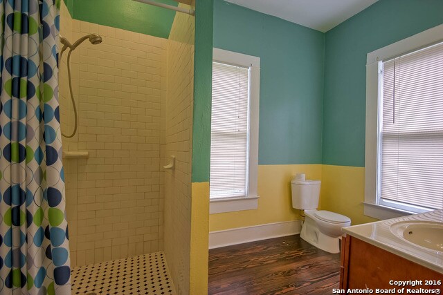 bathroom with toilet, vanity, wood-type flooring, and curtained shower