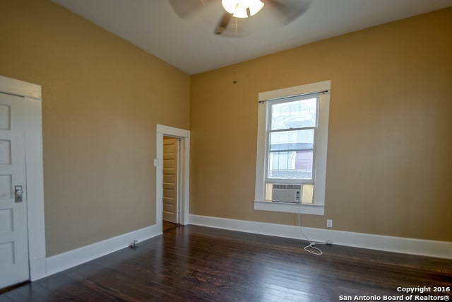 empty room featuring dark wood-type flooring, cooling unit, and ceiling fan