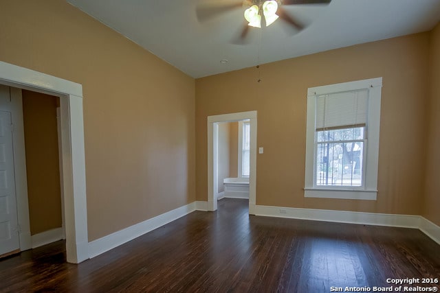 empty room with dark hardwood / wood-style flooring and ceiling fan