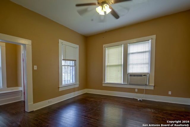 spare room with dark hardwood / wood-style flooring, cooling unit, and ceiling fan