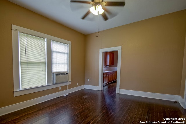 spare room with dark hardwood / wood-style flooring, cooling unit, and ceiling fan