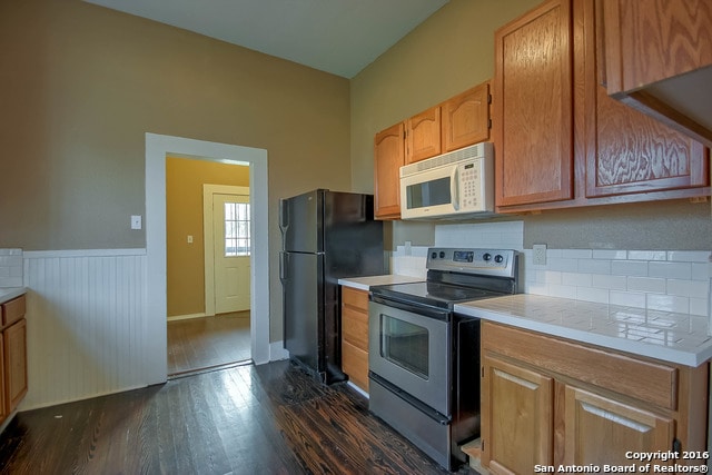 kitchen featuring black refrigerator, stainless steel range with electric cooktop, and dark hardwood / wood-style floors