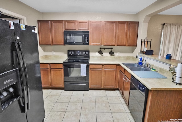 kitchen featuring black appliances, light tile patterned floors, and sink