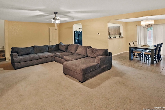 carpeted living room featuring ceiling fan with notable chandelier