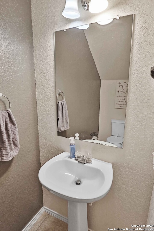 bathroom with toilet, sink, and tile patterned floors