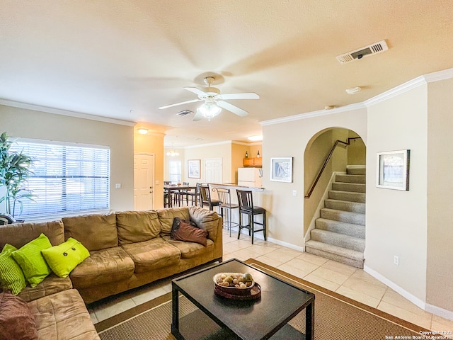 tiled living room with ceiling fan and crown molding