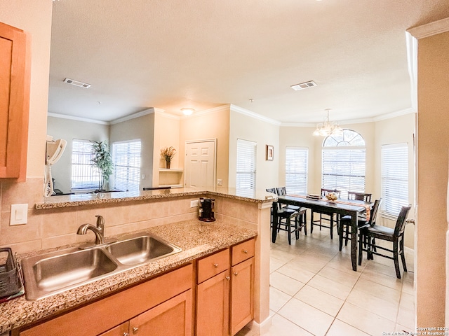 kitchen featuring decorative light fixtures, sink, light tile patterned floors, and ornamental molding