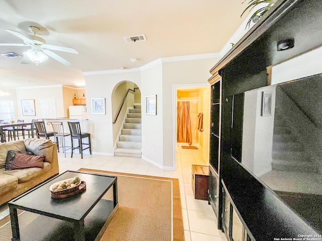 tiled living room with ceiling fan and crown molding