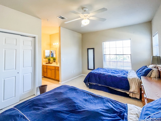 carpeted bedroom featuring ceiling fan, ensuite bath, and a closet