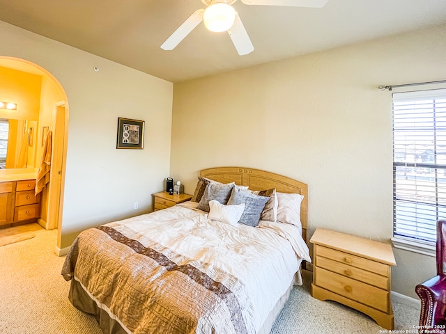 bedroom with ceiling fan, connected bathroom, and light colored carpet