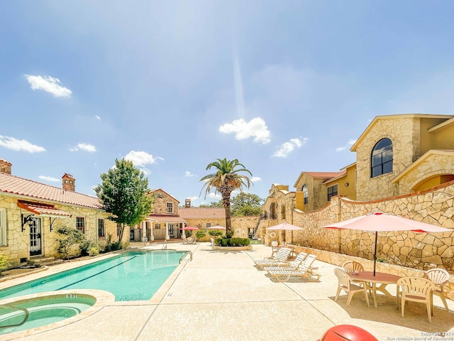 view of swimming pool with a hot tub and a patio area