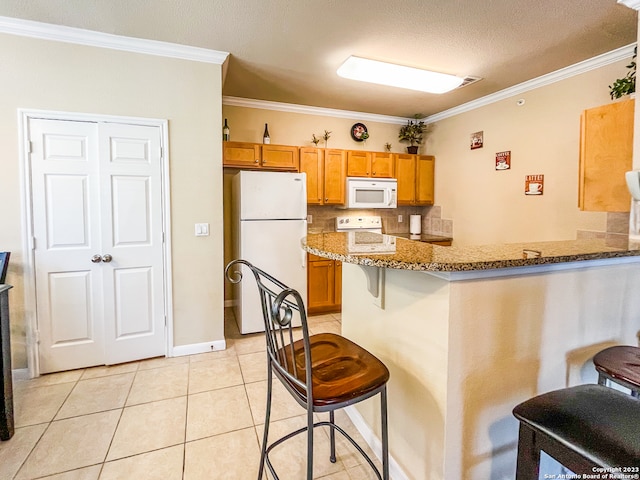 kitchen with kitchen peninsula, ornamental molding, a breakfast bar, light stone countertops, and white appliances