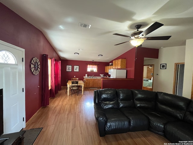 living room with ceiling fan, a healthy amount of sunlight, light wood-type flooring, and vaulted ceiling