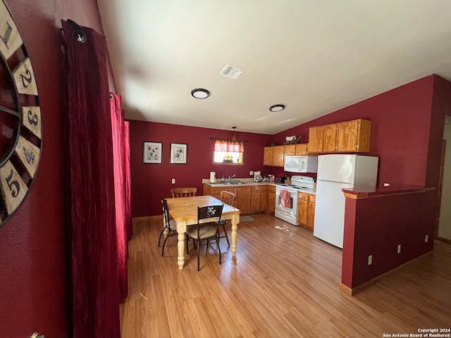 kitchen featuring light wood-type flooring, white appliances, sink, pendant lighting, and lofted ceiling