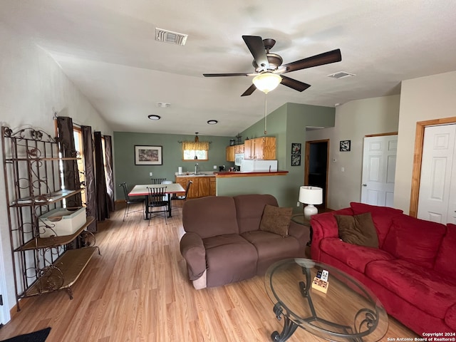 living room featuring hardwood / wood-style flooring, ceiling fan with notable chandelier, lofted ceiling, and sink