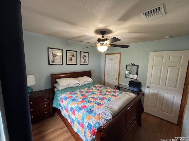 bedroom with ceiling fan, hardwood / wood-style floors, and a textured ceiling