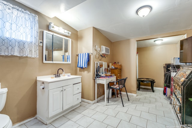 bathroom featuring toilet, vanity, lofted ceiling, and an AC wall unit