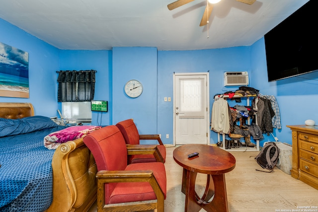 bedroom featuring light wood-type flooring, a wall unit AC, and ceiling fan