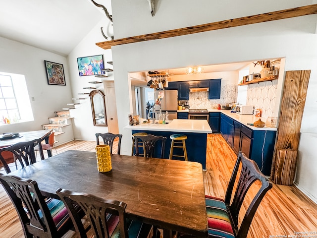 dining area with light wood-type flooring and vaulted ceiling