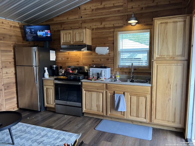 kitchen with dark wood-type flooring, vaulted ceiling, wood walls, sink, and appliances with stainless steel finishes