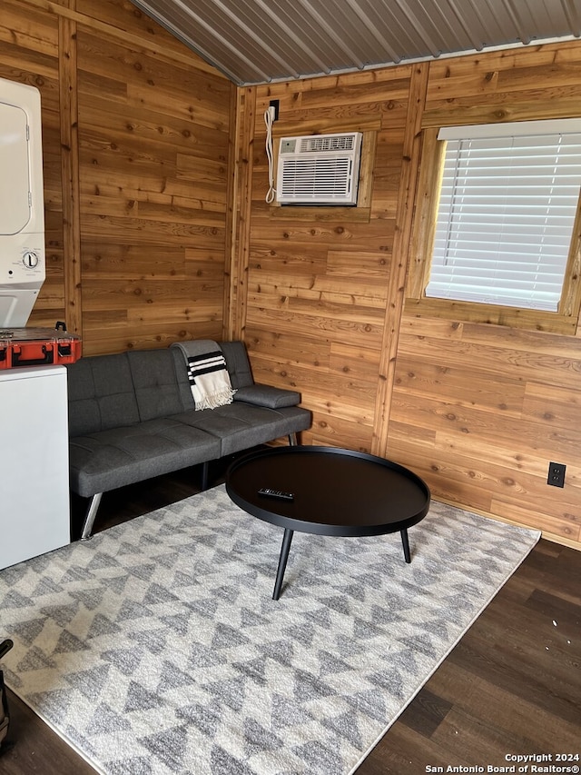 living room featuring dark hardwood / wood-style flooring, stacked washing maching and dryer, wooden walls, wooden ceiling, and an AC wall unit