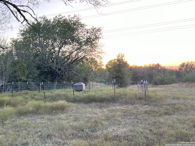 yard at dusk featuring a rural view