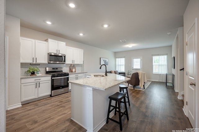 kitchen with white cabinetry, a center island with sink, stainless steel appliances, and a breakfast bar area