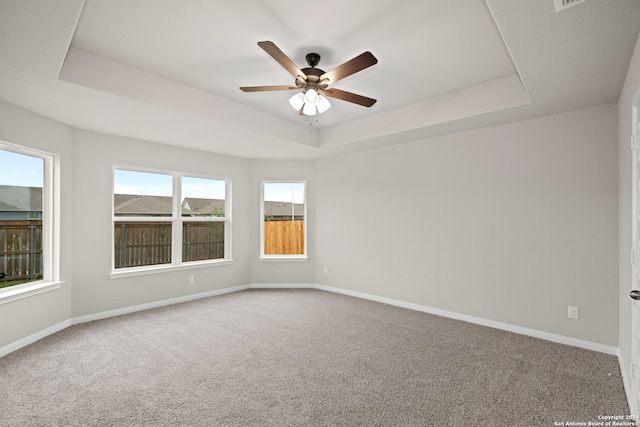 spare room featuring carpet floors, ceiling fan, and a raised ceiling